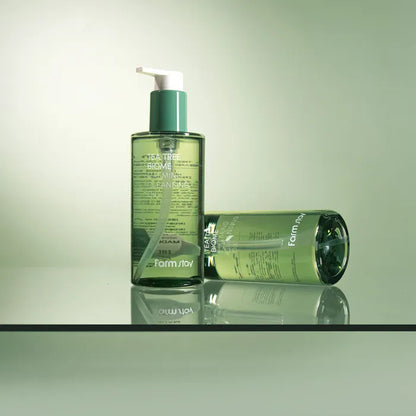 Two green bottles of Farmstay Tea Tree Calming Cleansing Oil with pump dispenser on a reflective surface - ken cosmetics lebanon